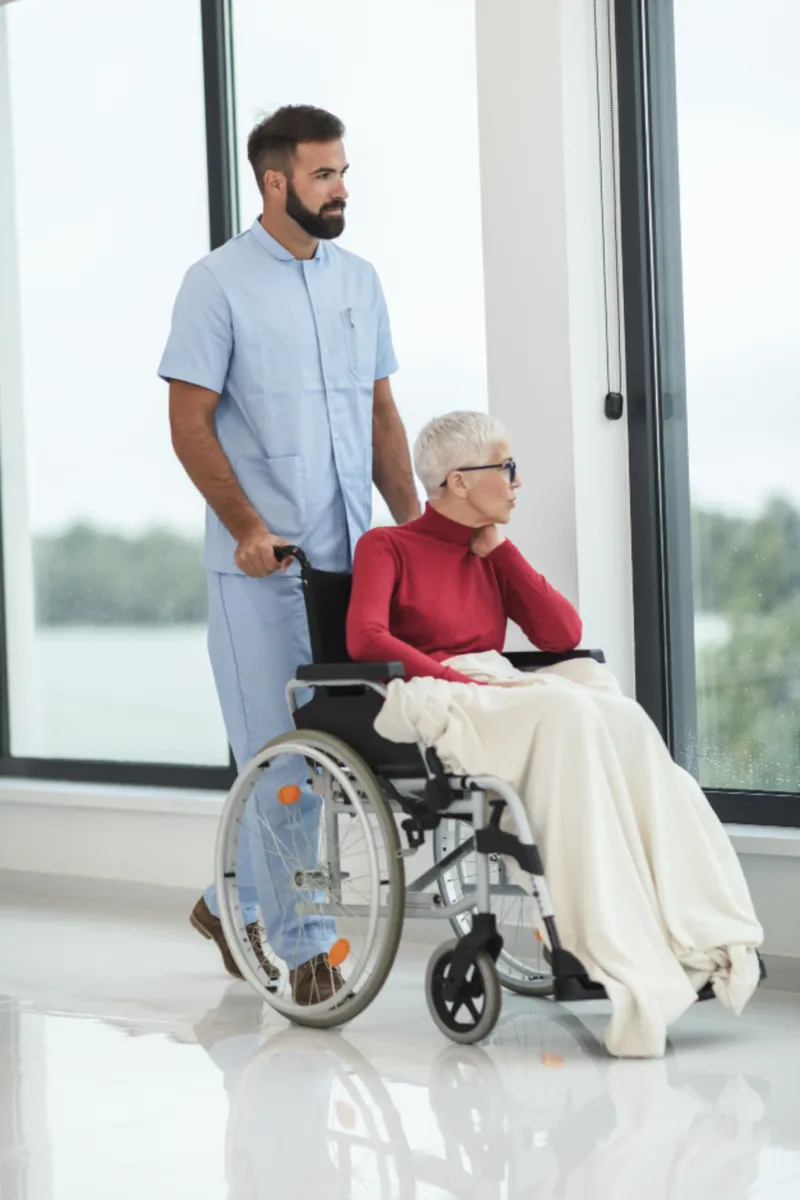 A caregiver wheeling a patient through a bright hospital hallway